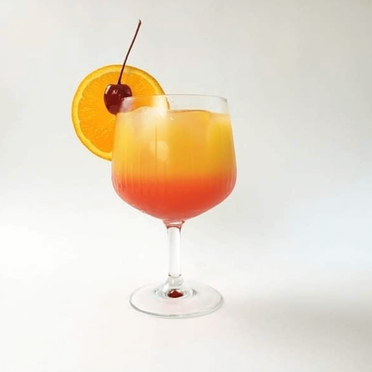 orange and red drink with an orange slice and cherry
